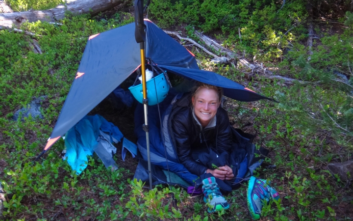 a person smiles from under a shelter in a green area